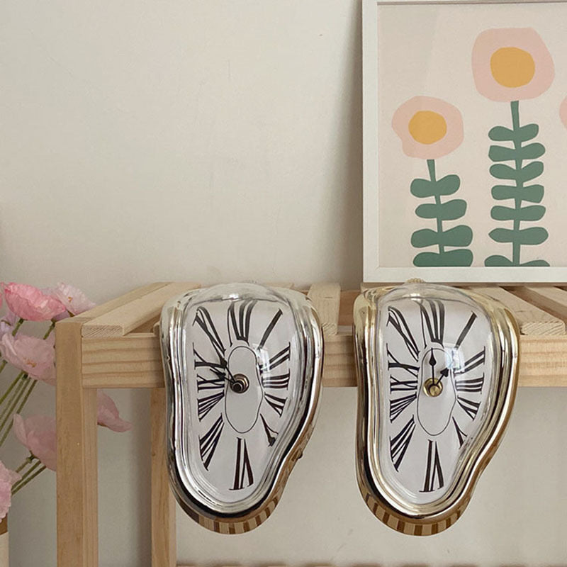 Gold Dali-inspired melting clock on a desk for surrealist decor.