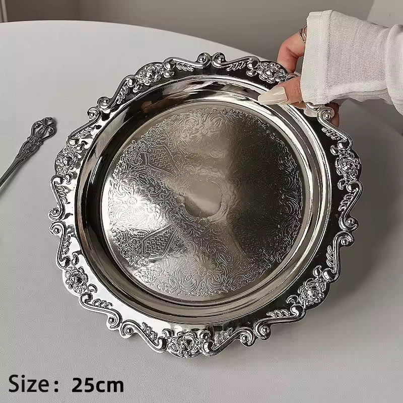 Decorative silver tray with intricate designs held by a hand on a light background