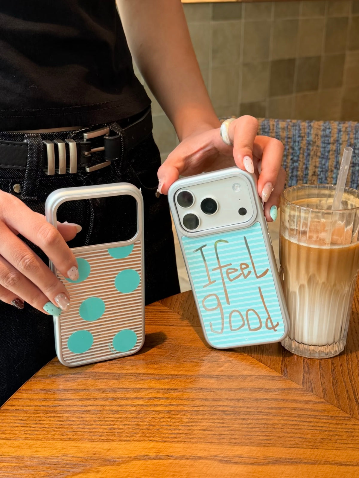 A closer upright view shows silver striped iPhone cases with aqua dots on one and Feel Good lettering on the other.