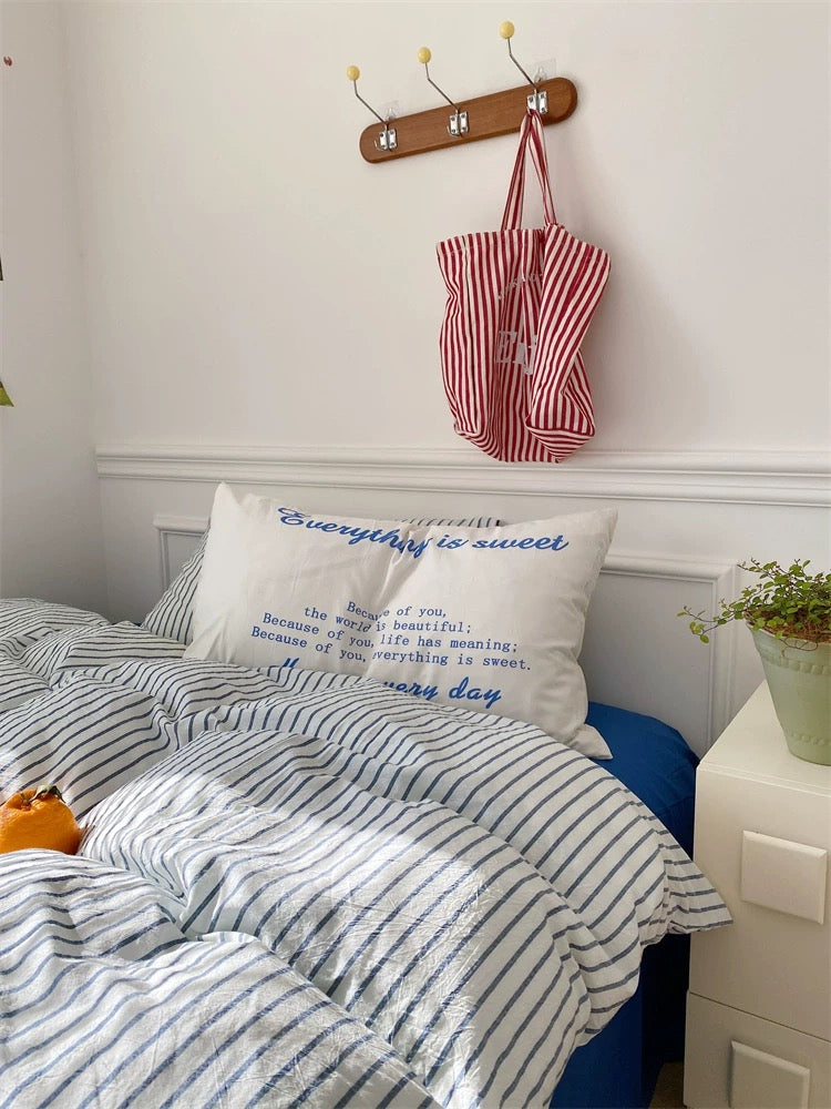 Bedroom with striped bedding and a red and white bag hanging on a hook.