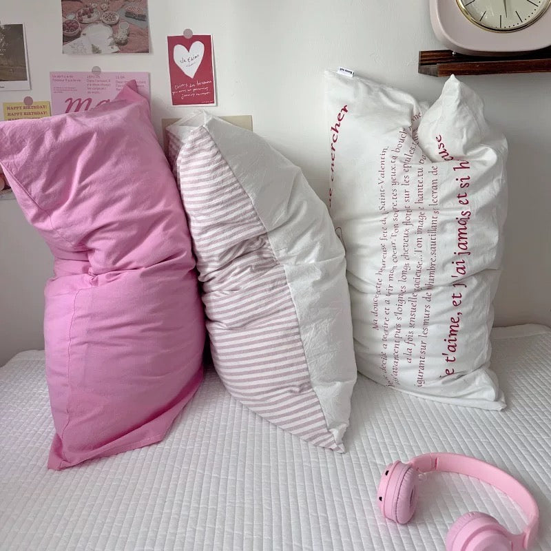 Three pillows on a bed with pink headphones and text on the pillows.