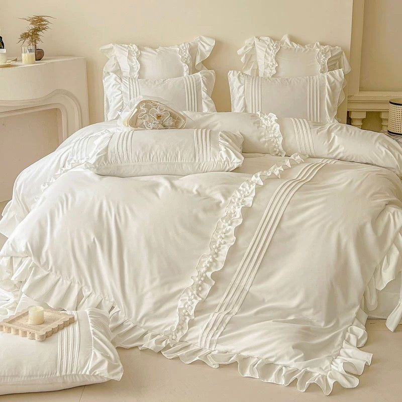 White ruffled bedding set on a bed in a bedroom setting.