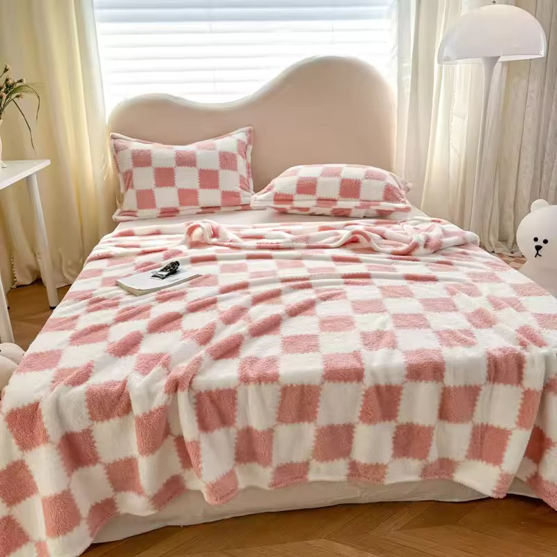 Bed with pink and white checkered blanket and pillows in a cozy room.