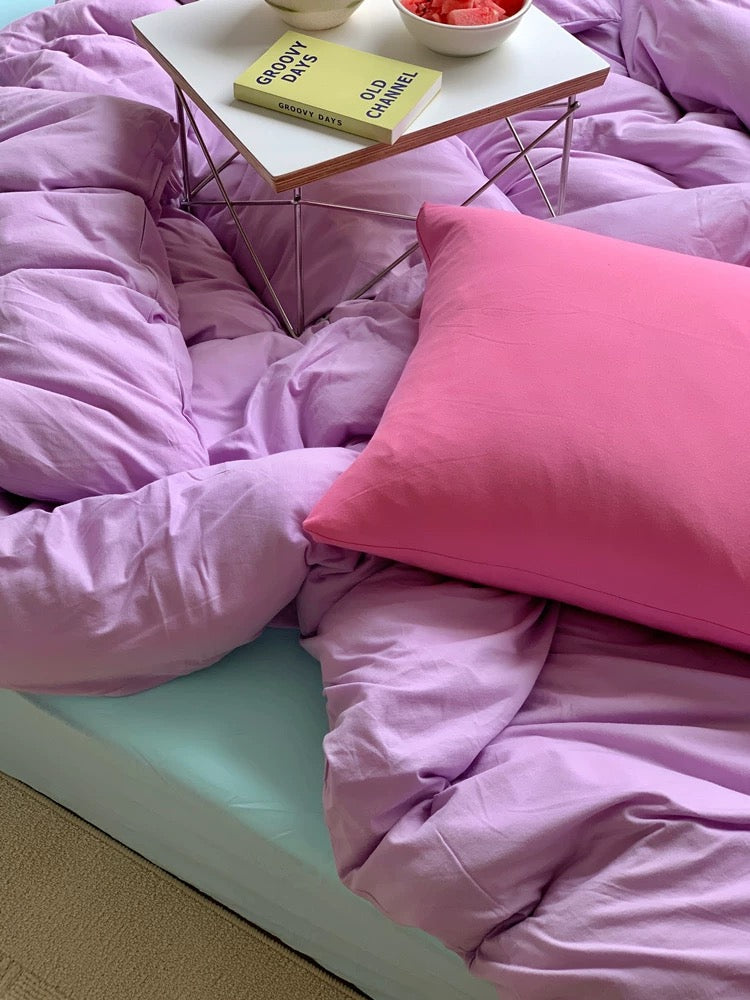Pink bedding with a small table and books on a bed.