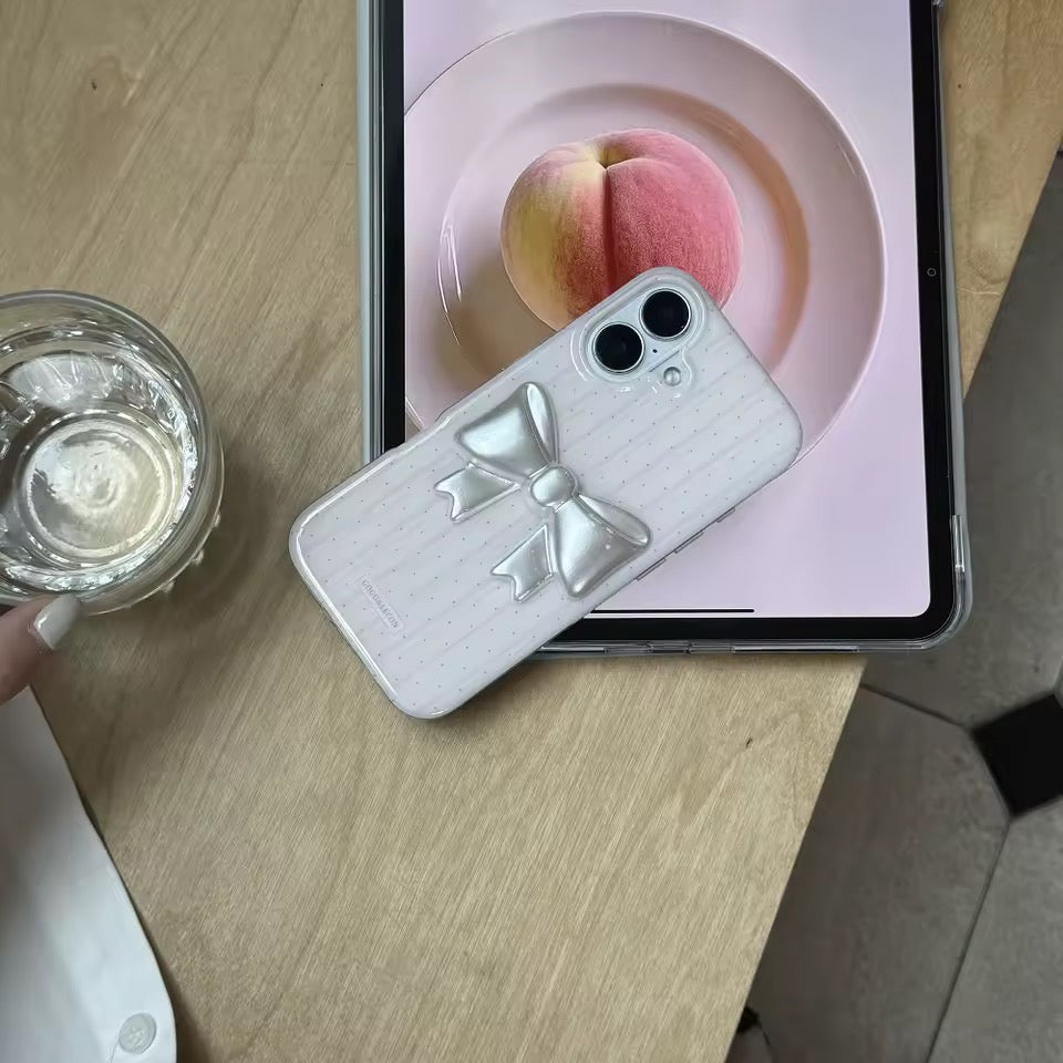 Phone case with bow design next to a tablet displaying a peach on a pink background