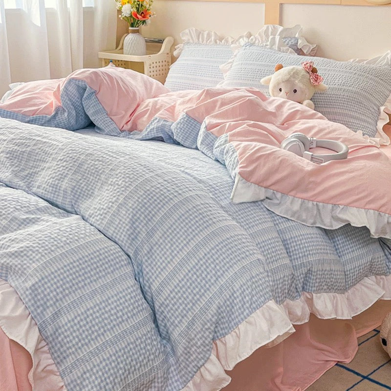 Bed with pink and blue checkered bedding and a teddy bear.