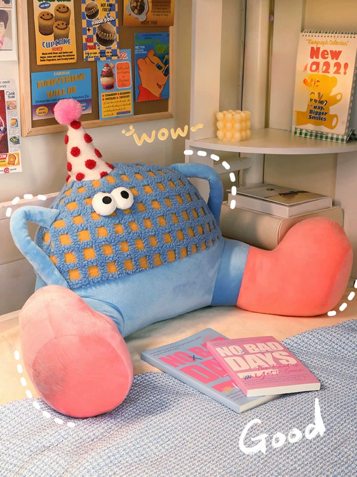Children's room with a blue and pink cushion, books, and a calendar on a shelf.