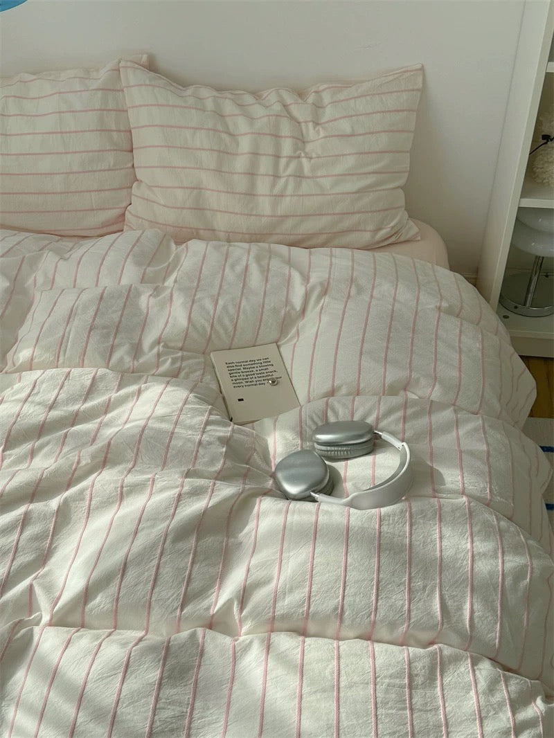 White comforter with red stripes on a bed, featuring a tag and decorative item.
