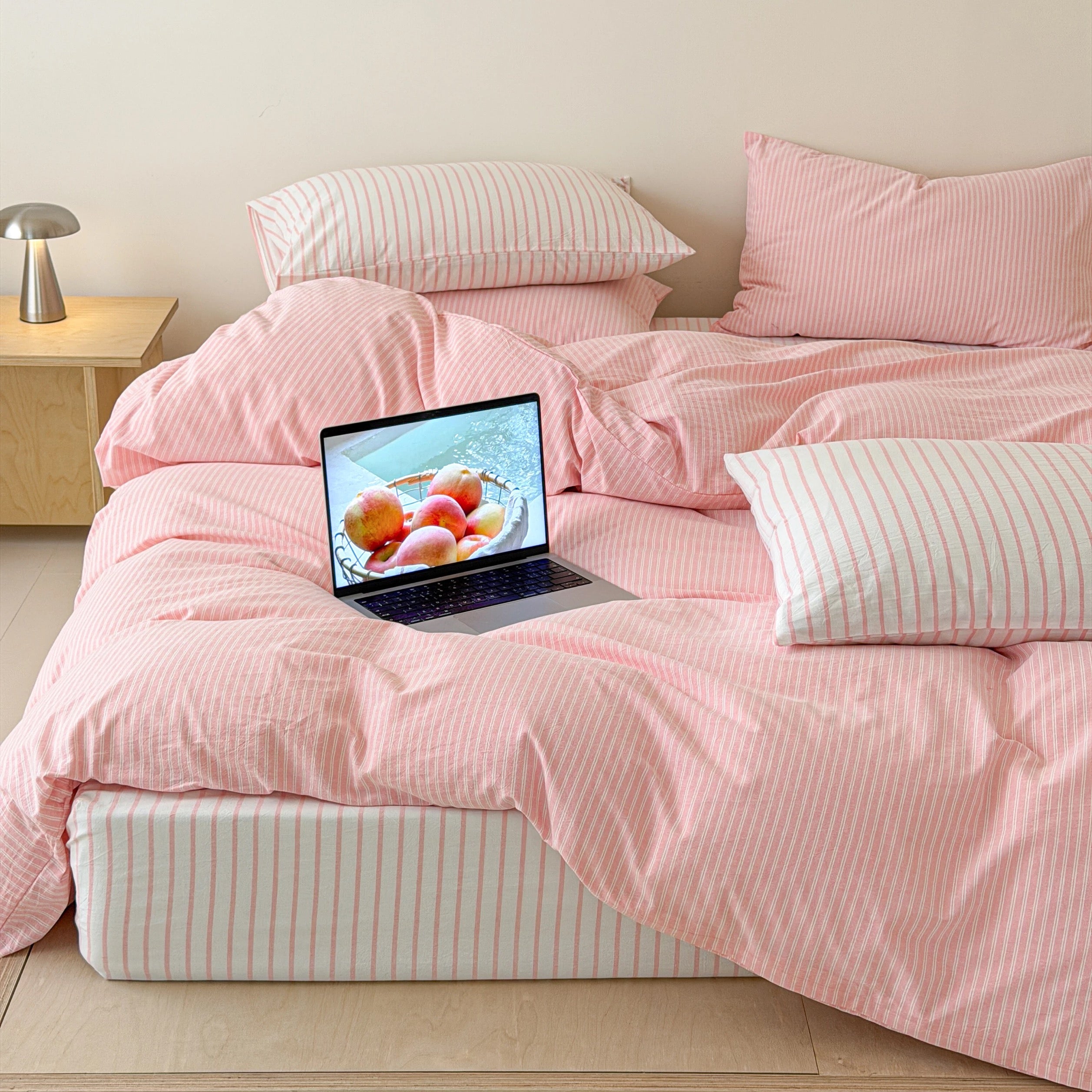 Scandinavian bedroom styled using blush striped cotton duvet cover and coordinating pillowcases on wooden platform bed.