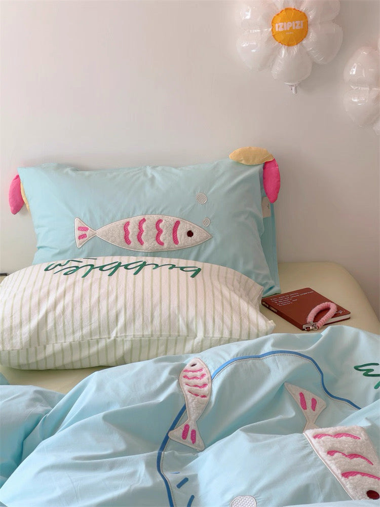 Pastel bedding set with cartoon fish embroidery, styled with fairy lights and pastel accents.