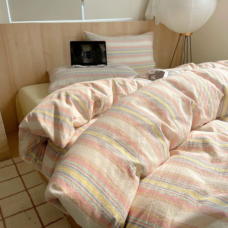 Bed with striped bedding in a room with a window and lamp.
