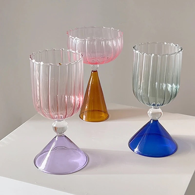 Stemmed cocktail glass with blue and pink accents, gold rim, and sculptural transparent glass shape.
