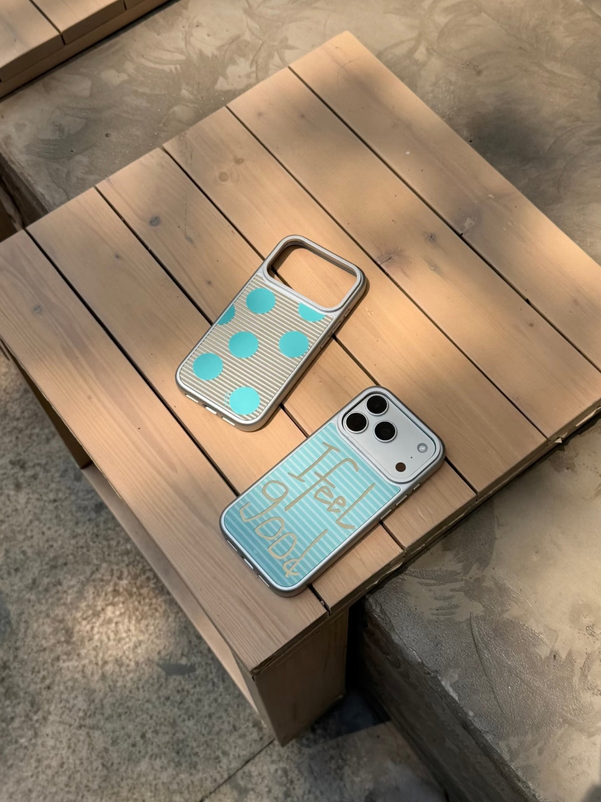Both striped iPhone case designs lie at an angle, with the aqua polka dot design above the lettering design.
