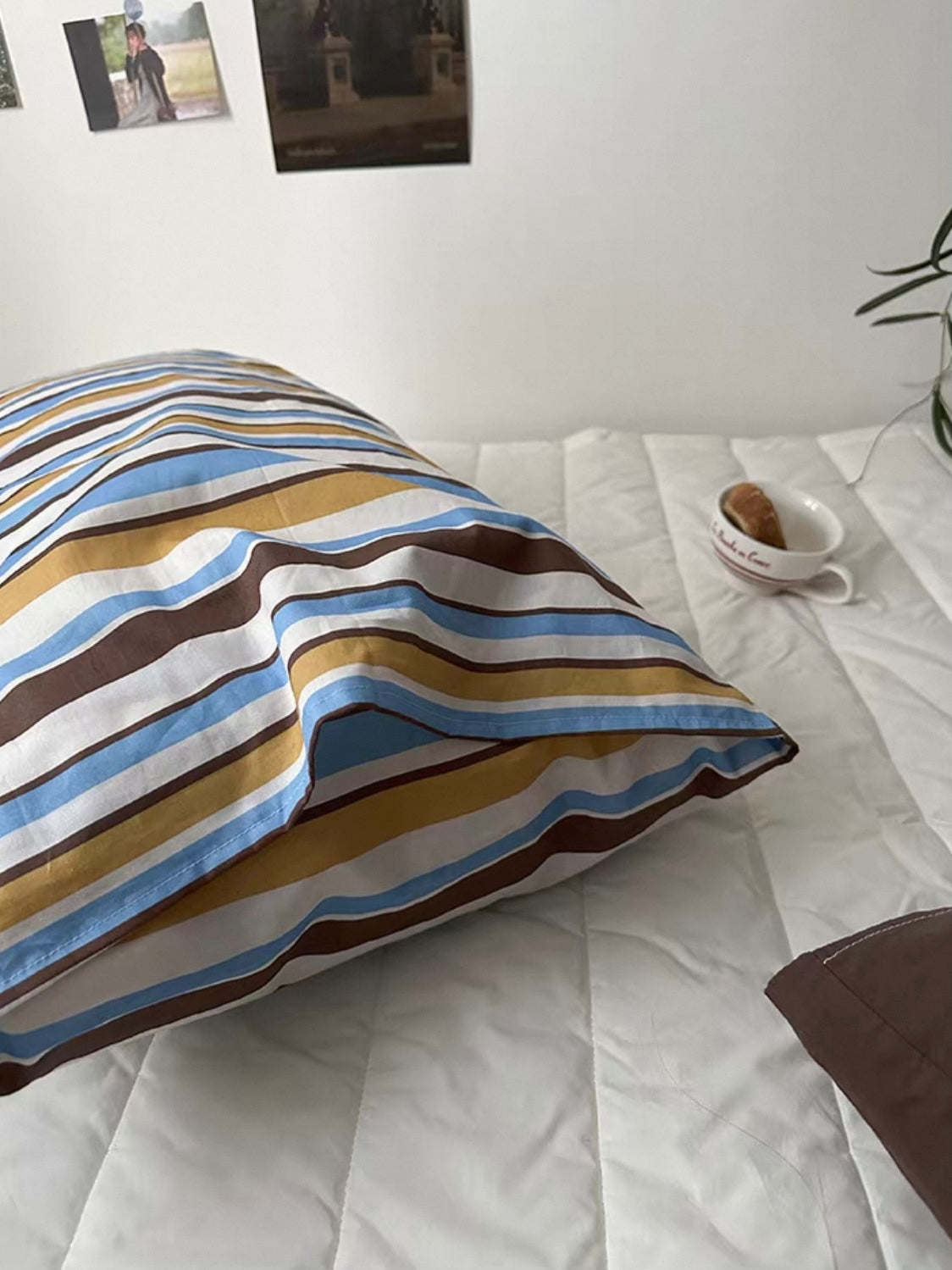 A close view of the striped pillow case shows blue, yellow and brown bands separated by light stripes.