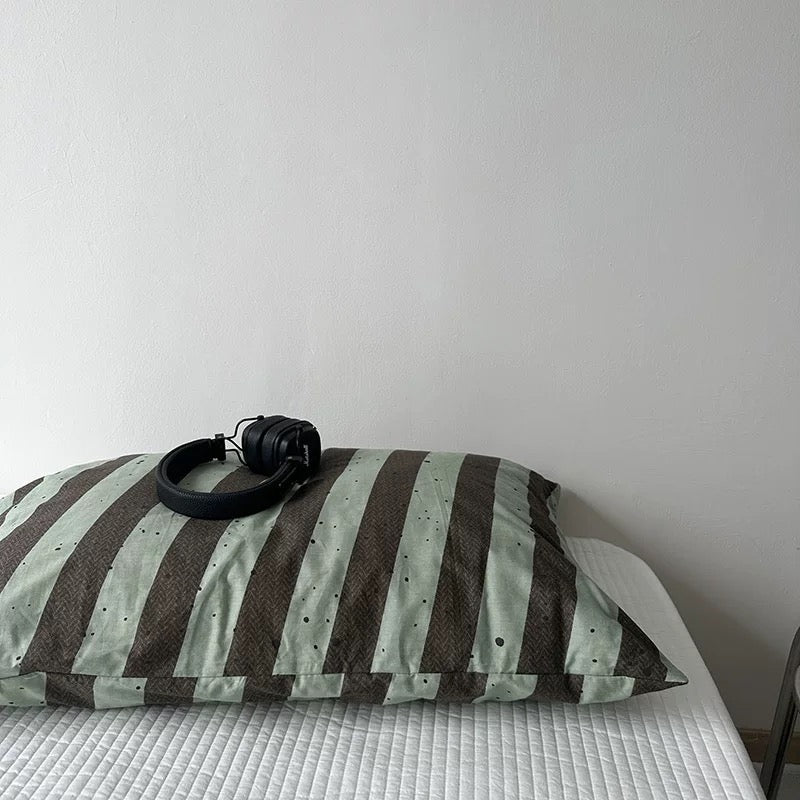 Striped pillow with headphones on a bed against a plain wall