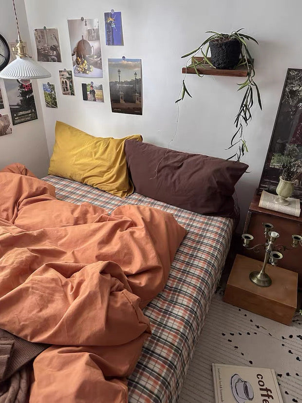 Terracotta cotton duvet cover styled with brown pillows and plaid bedding in cozy vintage bedroom.