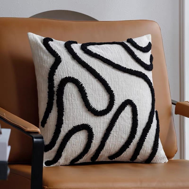 Decorative pillow with black abstract patterns on a brown chair