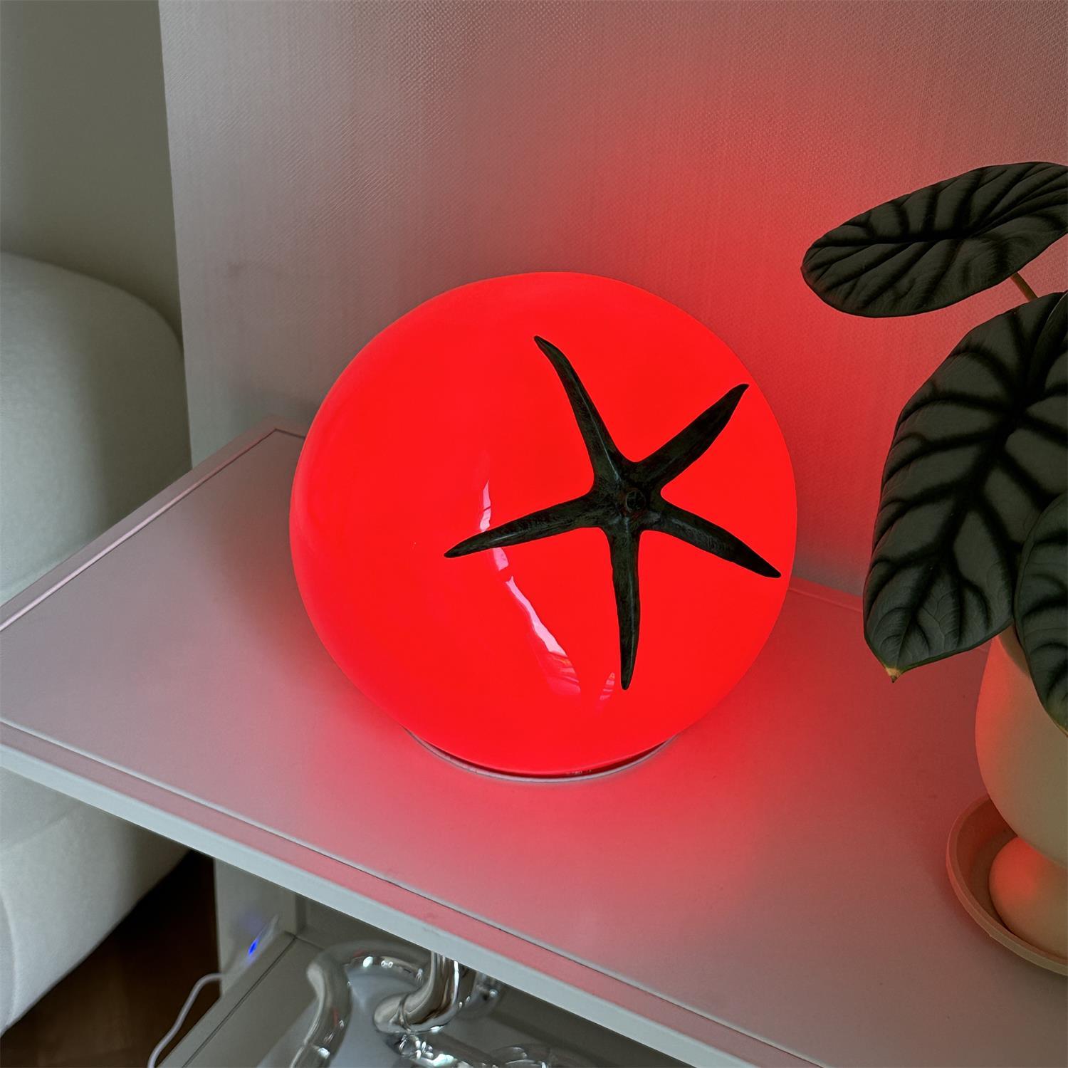 Red circular light with a black star-like design on a white surface.