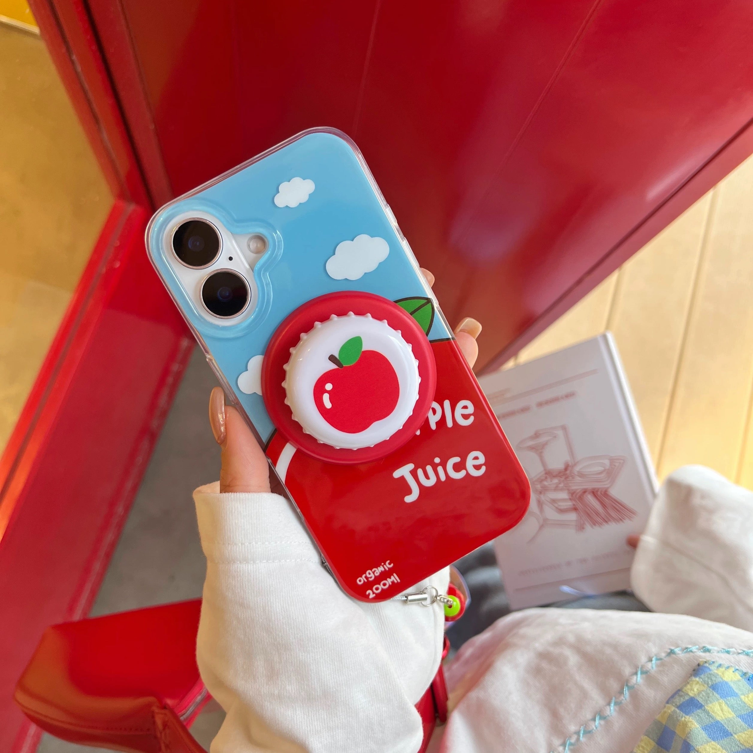 Phone case with apple design held by a person against a red background