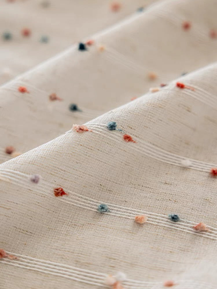 Airy cotton-linen sheers hanging in a bright minimalist bedroom.