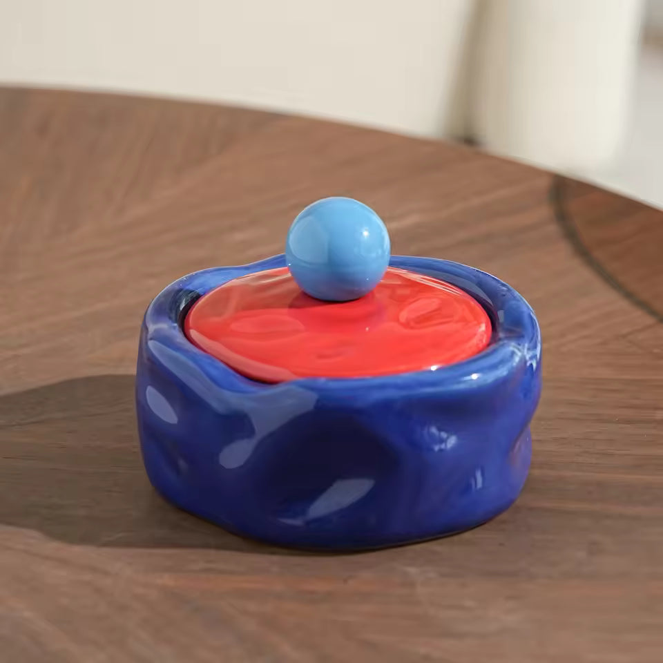Colorful ceramic container with a blue ball on top on a wooden surface