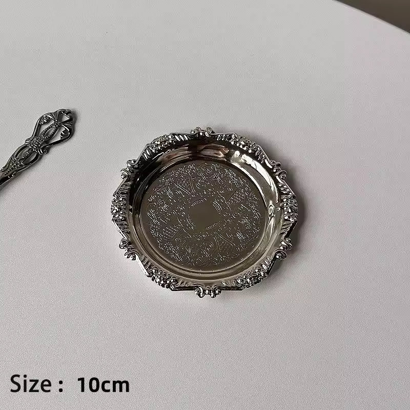 Decorative silver plate with intricate designs on a light gray background