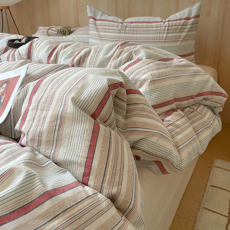 Bed with striped bedding and a magazine on a wooden nightstand in a room.