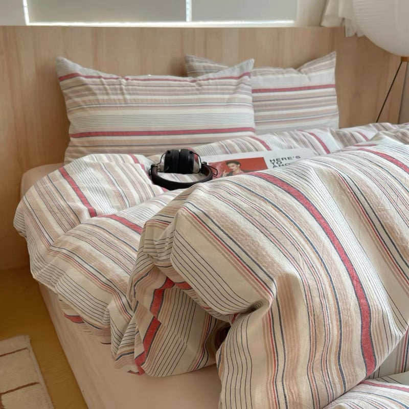 Striped bedding set on a bed with a wooden headboard
