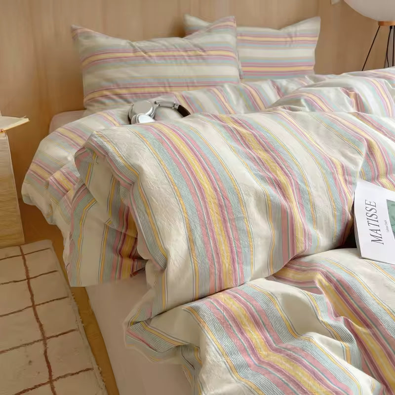 Striped bedding set on a bed with pillows and a lamp in the background.