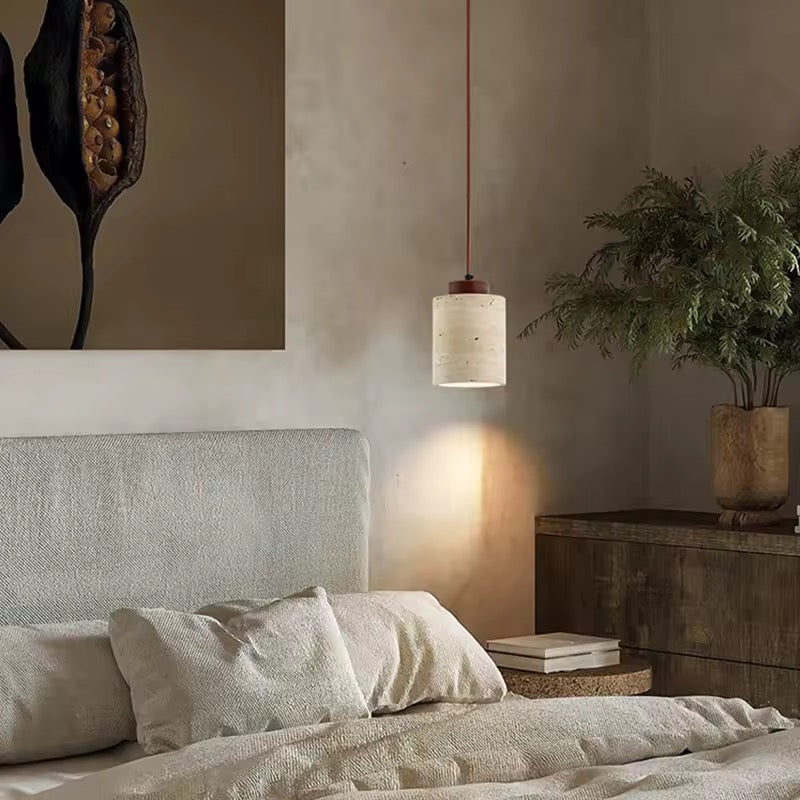 Wabi sabi stone pendant lamp with wood detail glowing softly over modern dining table setup.