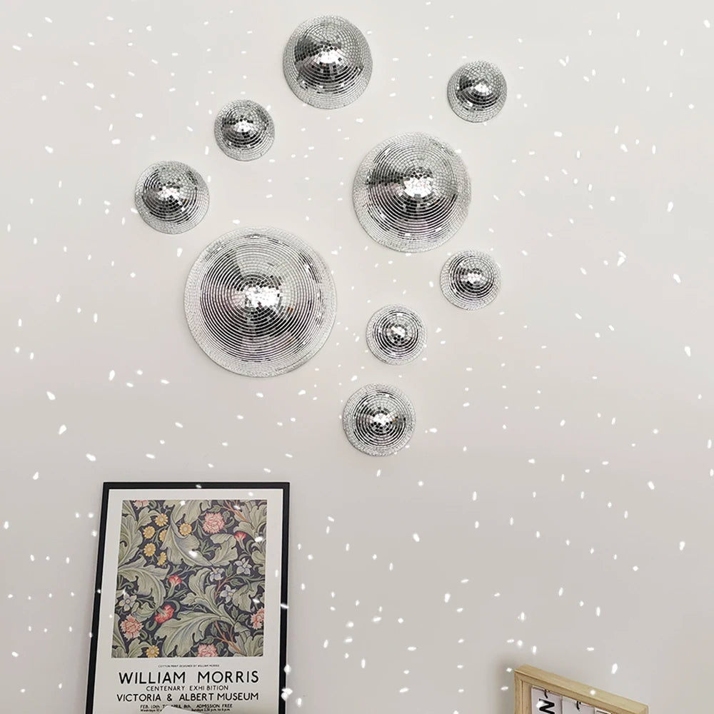 Decorative silver disco balls on a white wall with a framed picture below.