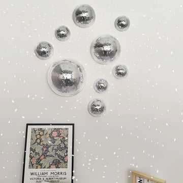 Decorative silver disco balls on a white wall with a framed picture below.