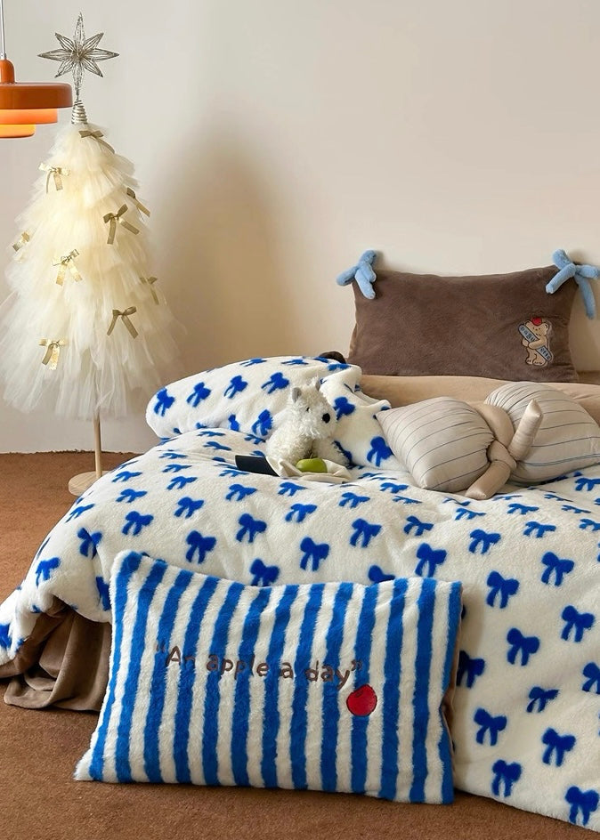 Children's bedroom with a bed covered in blue and white patterned bedding, surrounded by toys and a small Christmas tree.