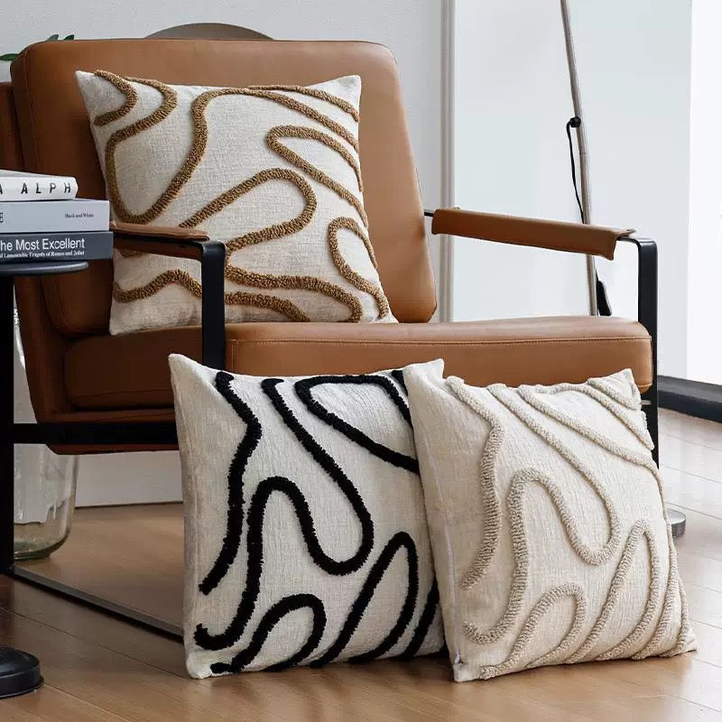 Decorative pillows with abstract patterns on a brown chair.