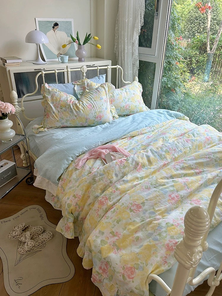 Watercolor floral gauze duvet cover set on a white metal bed beside a garden window