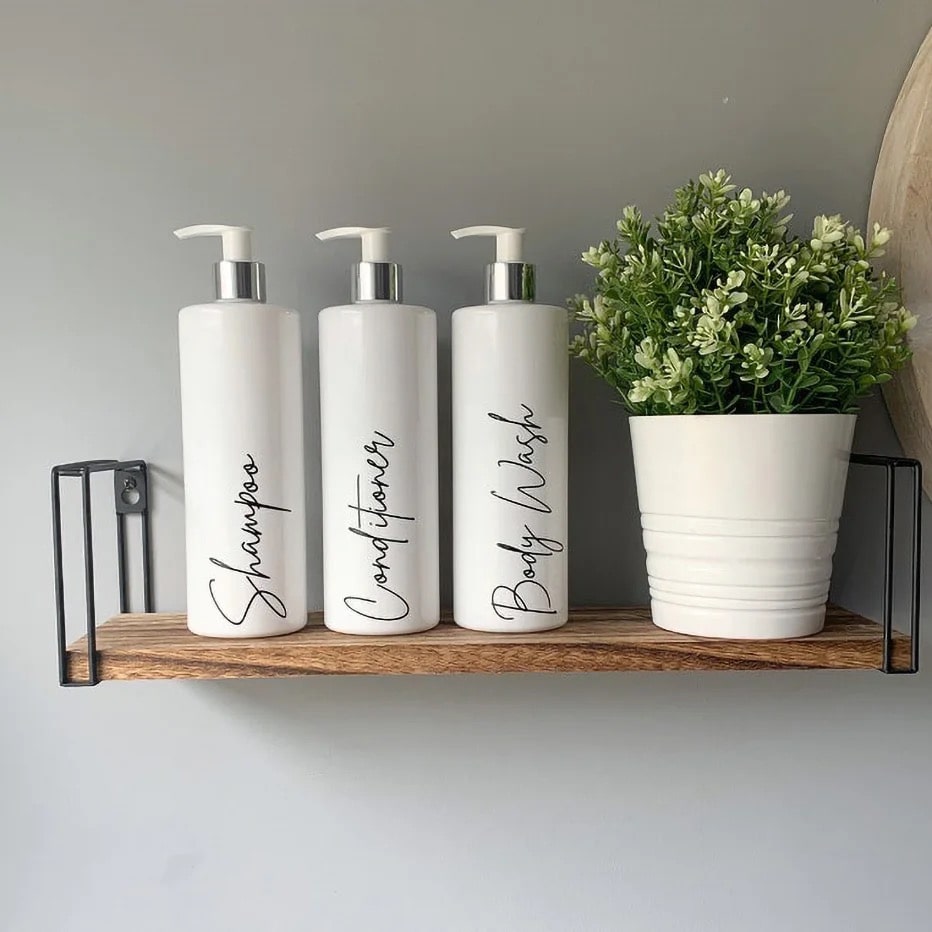 White bathroom dispenser set with 500ml refillable bottles for shampoo, conditioner, and lotion. Farmhouse decor with bamboo pump head design.
