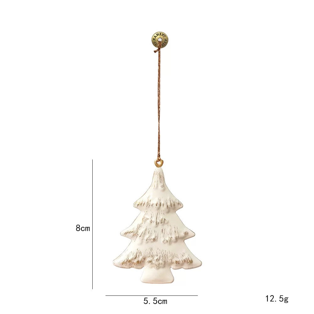 A white Christmas tree metal ornament has three branch tiers with gold colored marks across the surface.