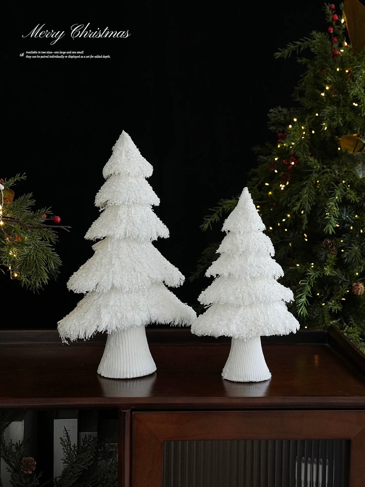 A white Christmas tree pair stands on a tabletop, showing two different heights and closely wrapped bases.