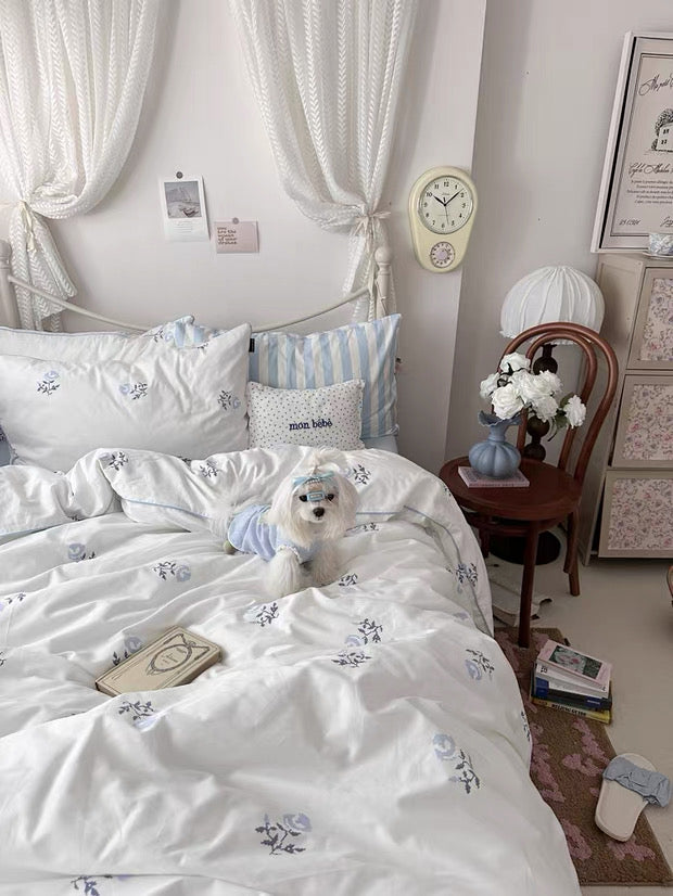 Bedroom with white canopy bed, striped pillows, and a clock on the wall.