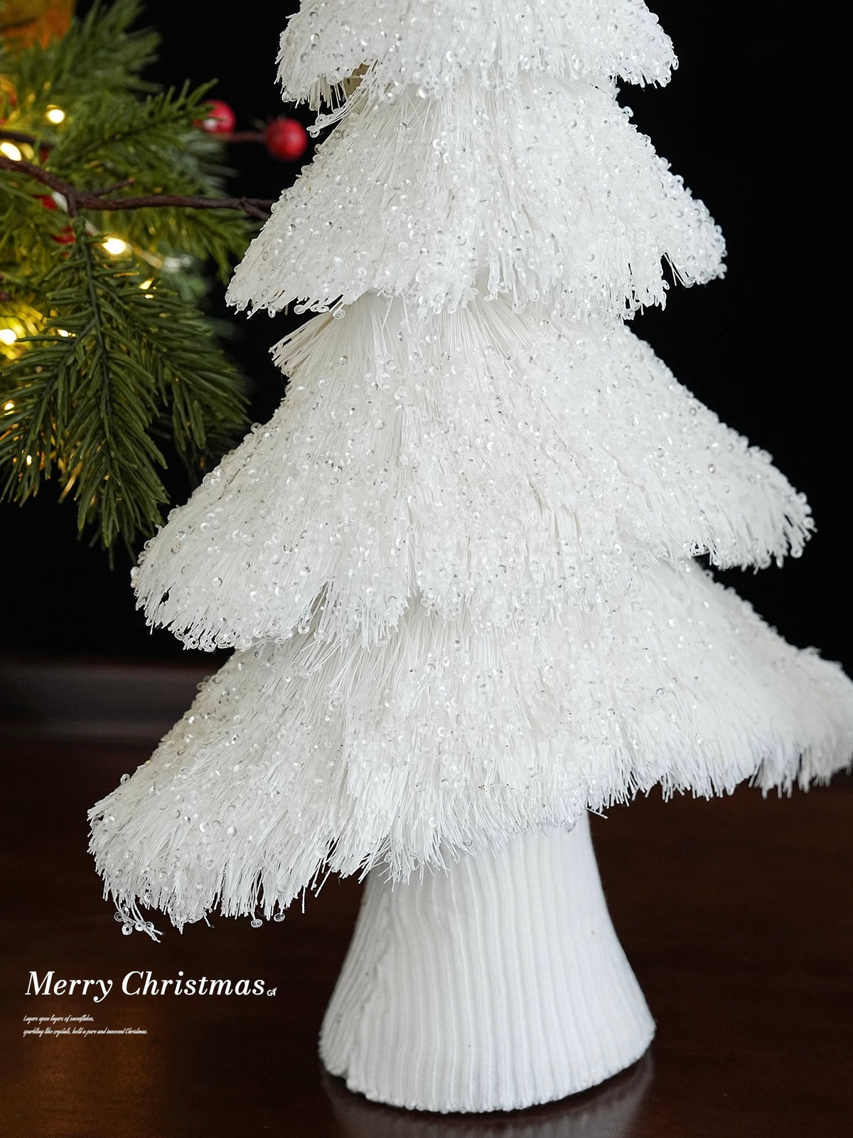 A white fringe Christmas tree shows overlapping lower branches above its tapered, closely wrapped base.