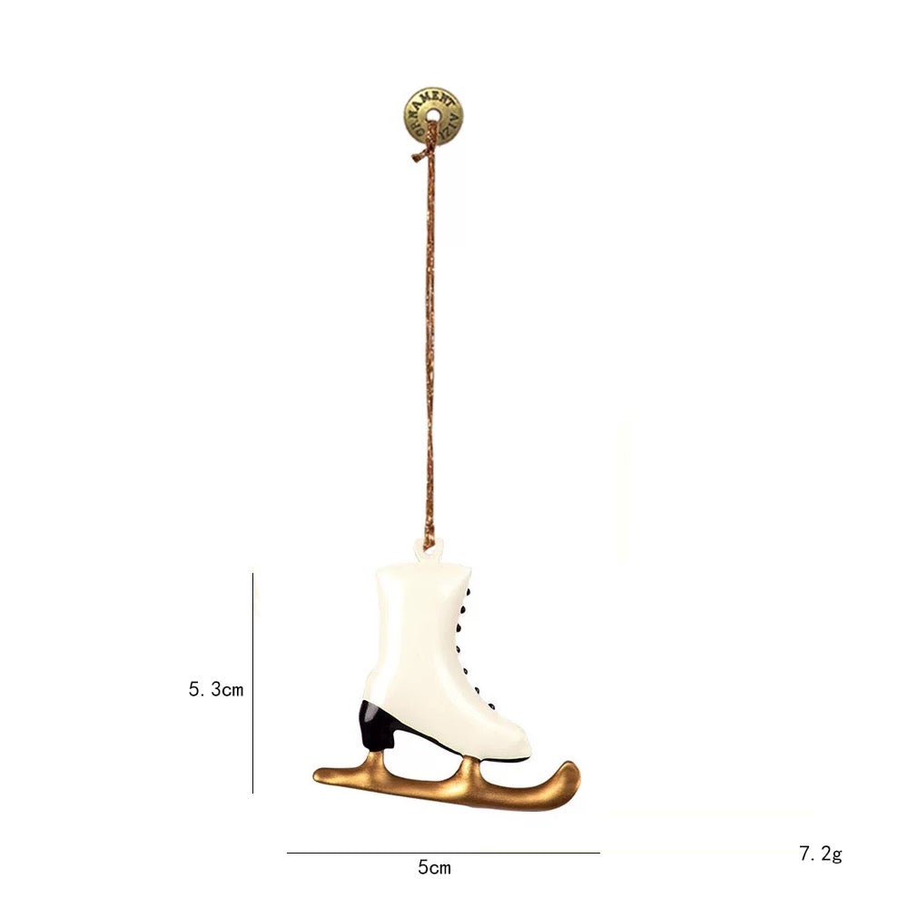 A white ice skate Christmas ornament has black lacing and a heel above a gold colored curved blade.