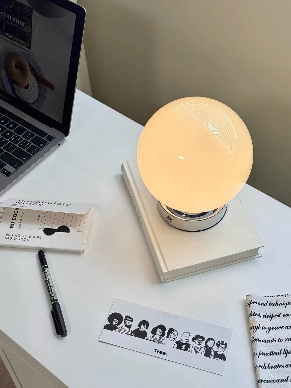 Lamp on a desk with a laptop, pen, and books