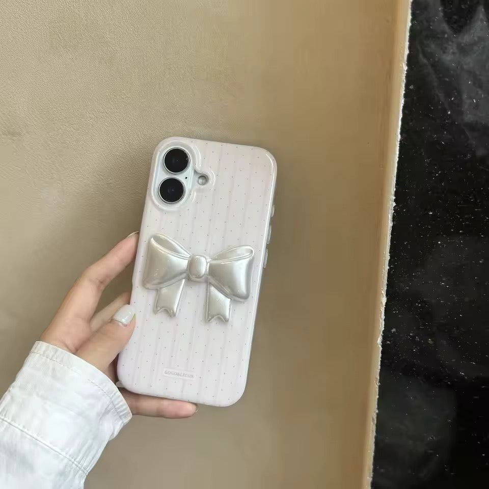 Phone case with a bow design held by a hand against a neutral background
