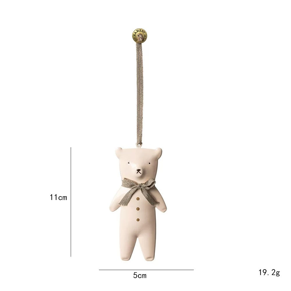 A white polar bear Christmas ornament has a gray bow around its neck and gold colored buttons on its body.
