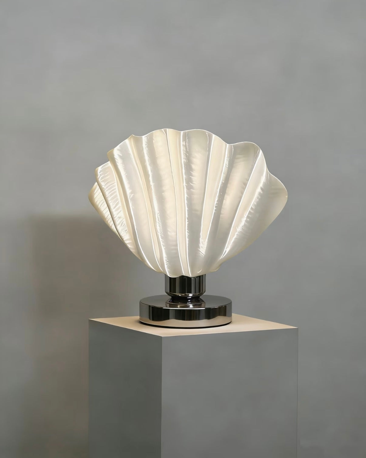 White scallop table lamp with shell relief design on bedside table creating soft warm ambient light