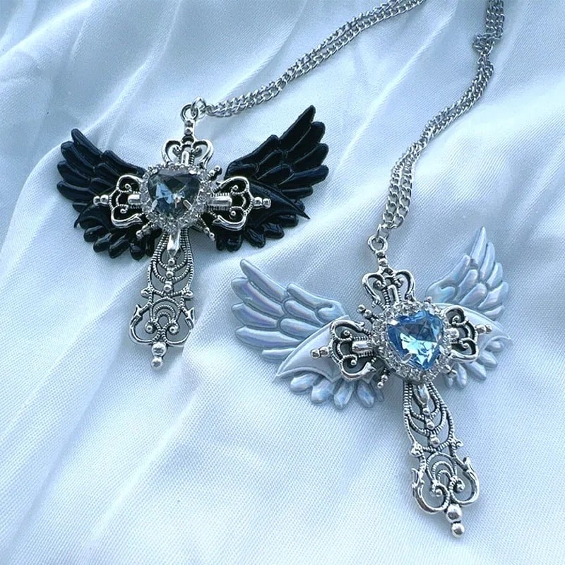 Gothic wing cross necklace with blue heart crystal. Angel wings pendant for women’s Y2K and punk aesthetic statement jewelry.