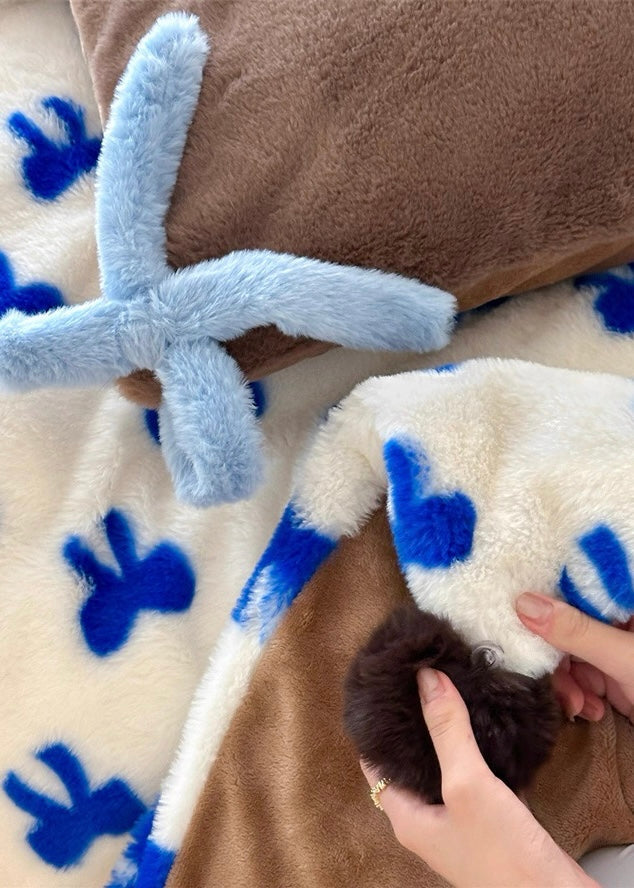 Close-up of a plush toy with blue antlers and brown body on a blanket with blue paw prints.
