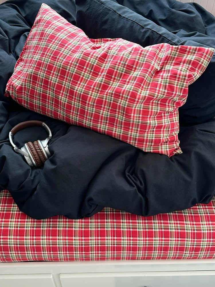 Red plaid pillow and headphones on a black blanket with a red checkered surface
