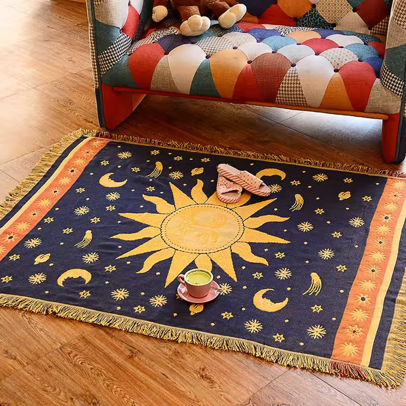 Decorative rug with sun and moon design on a wooden floor, next to a colorful patchwork sofa.