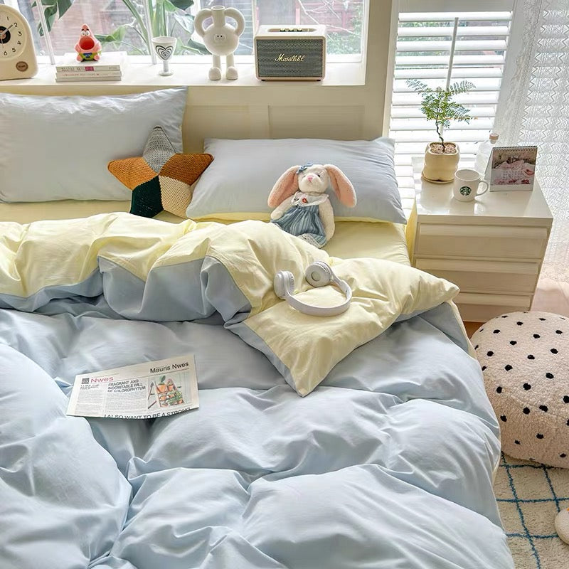 Bedroom with light blue and yellow bedding, plush toys, and a small nightstand.